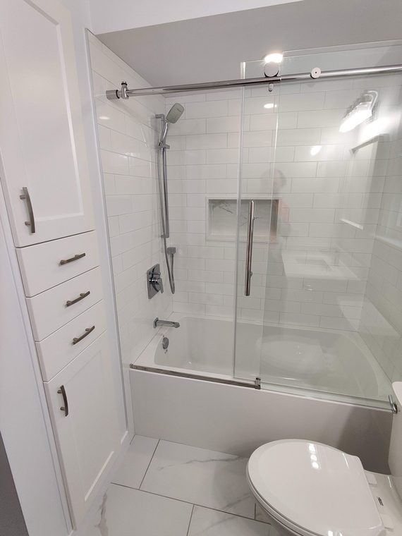 Glass shower screen fitted over a white bathtub