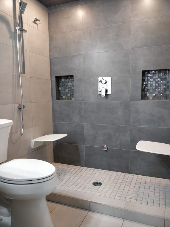 Walk in shower in dark grey tile with a mosaic niche