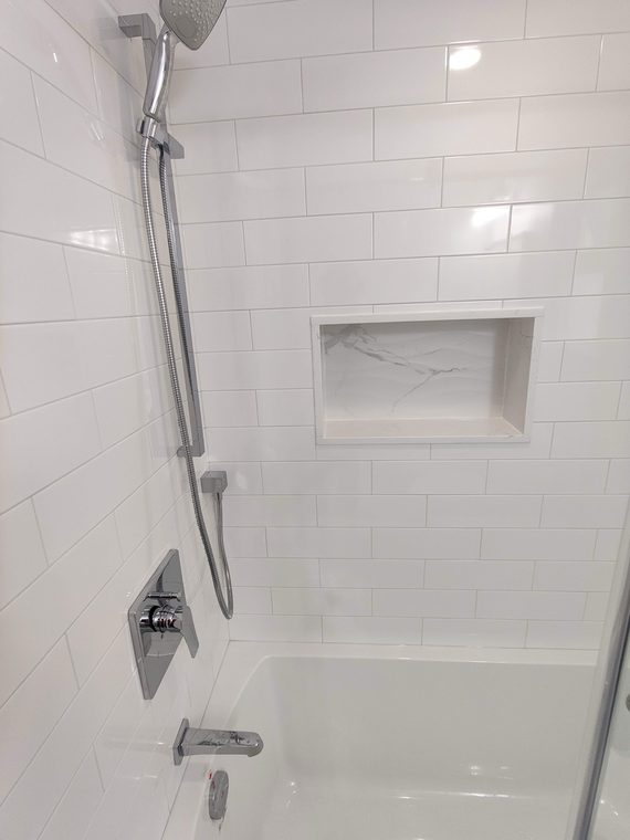 White tiled bathtub surround with a recessed niche