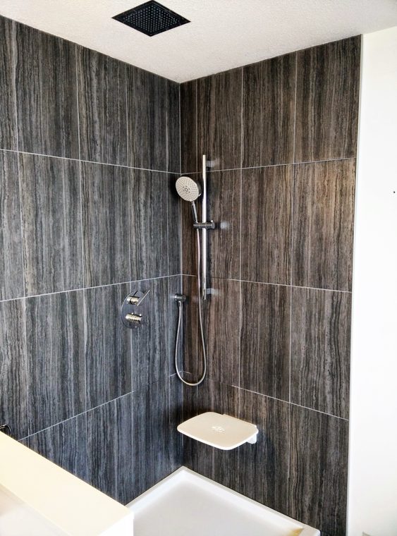 Walk in shower finished in full height dark stone tile