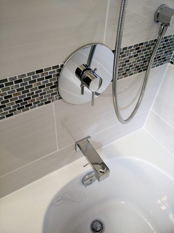 Tub filler and mosaic feature band in a tiled bathroom