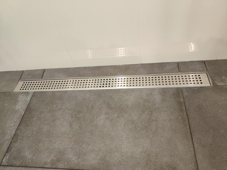 Linear drain set flush into a large format tiled shower floor