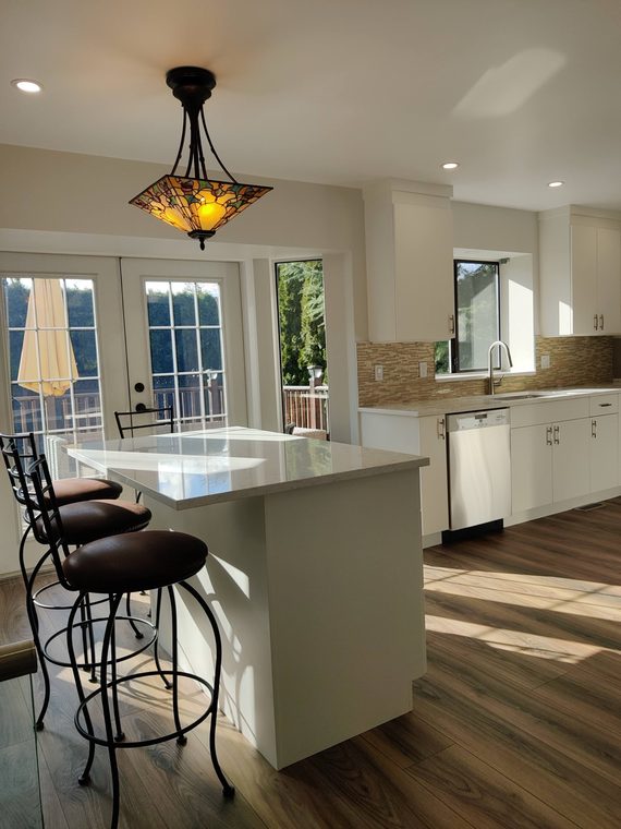 Open kitchen with an island, pendant light and pale flooring
